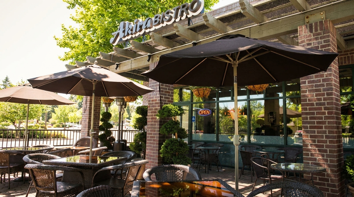 Outdoor patio of Akira Bistro with wicker tables, chairs, umbrellas, and a brick facade.