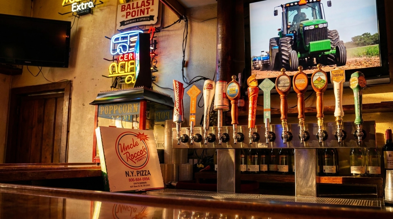 A bar counter with multiple beer taps, neon signs, and a TV showing a tractor.