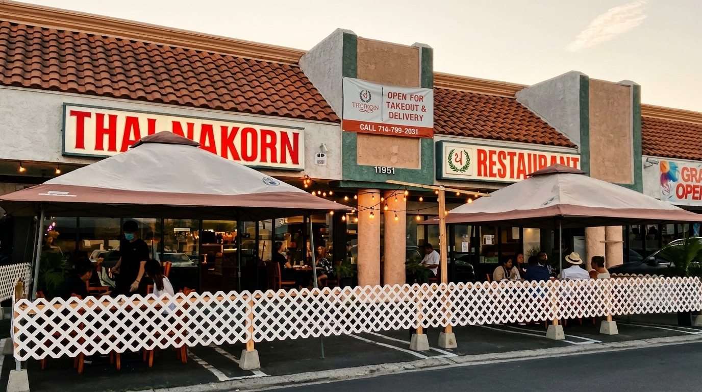 Thai Nakorn restaurant exterior with outdoor dining under umbrellas and string lights at dusk.