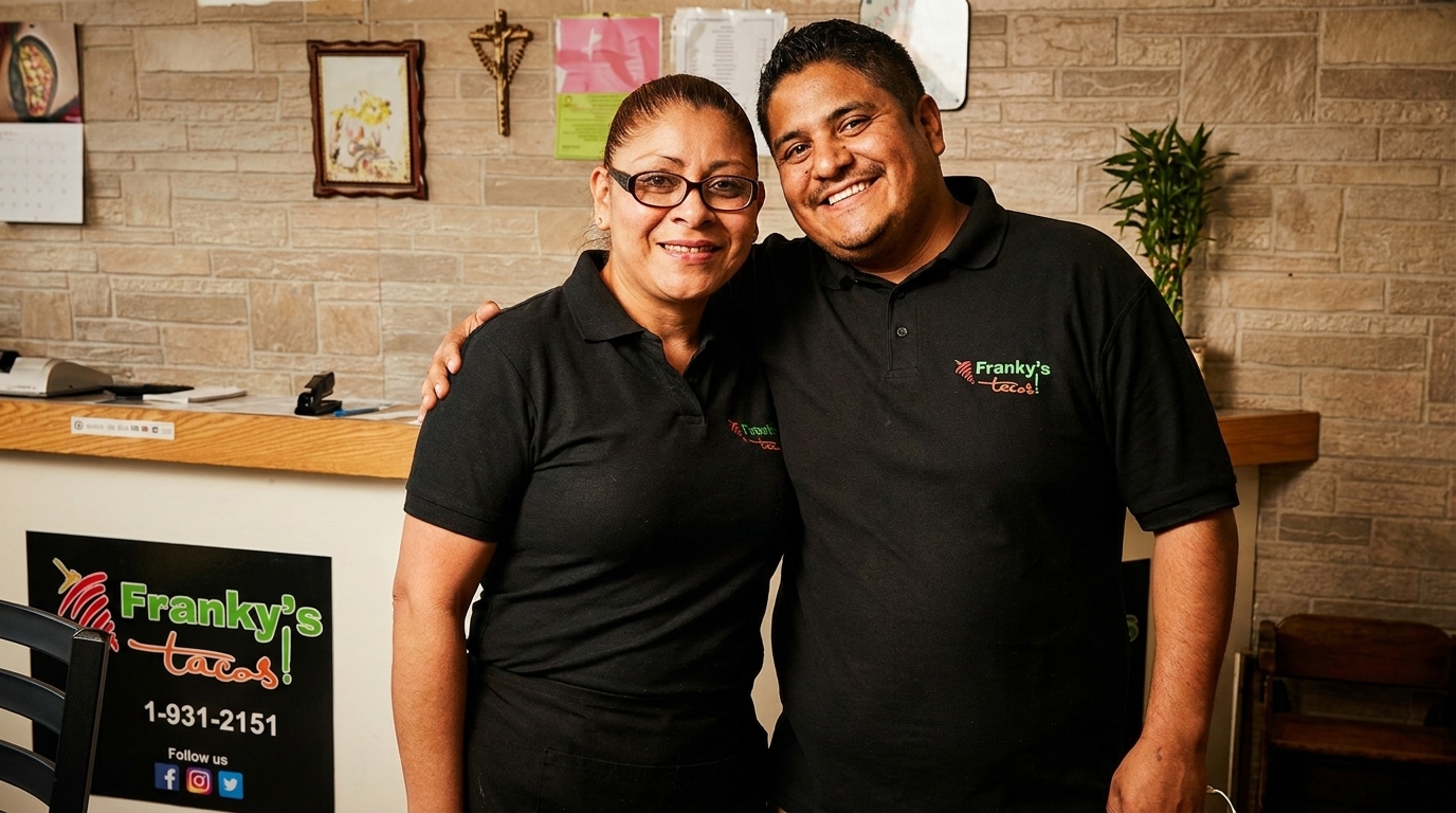 Two smiling Franky's Tacos employees, a man and a woman, stand together in the restaurant.