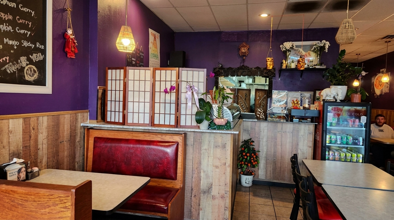 A restaurant interior with purple walls, wooden wainscoting, red booths, and Asian-inspired decor.