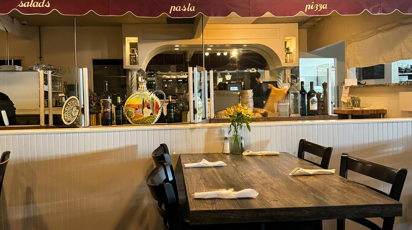 Restaurant interior with a wooden table set for dining, and a counter with bottles and decor.
