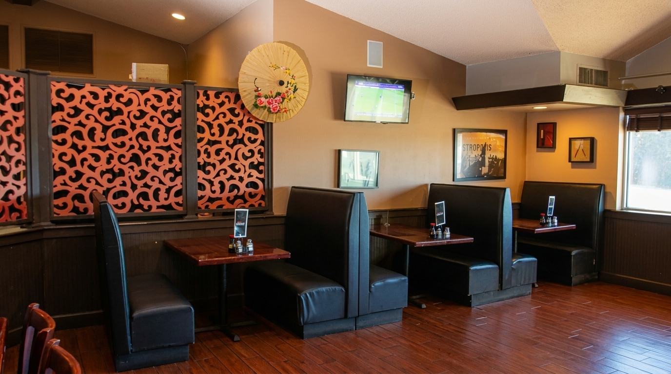 Cozy restaurant interior with dark booths, wooden tables, decorative screens, and a TV on the wall.