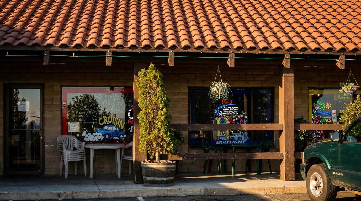 Exterior of a restaurant with a red tile roof, neon signs in windows, and outdoor seating.