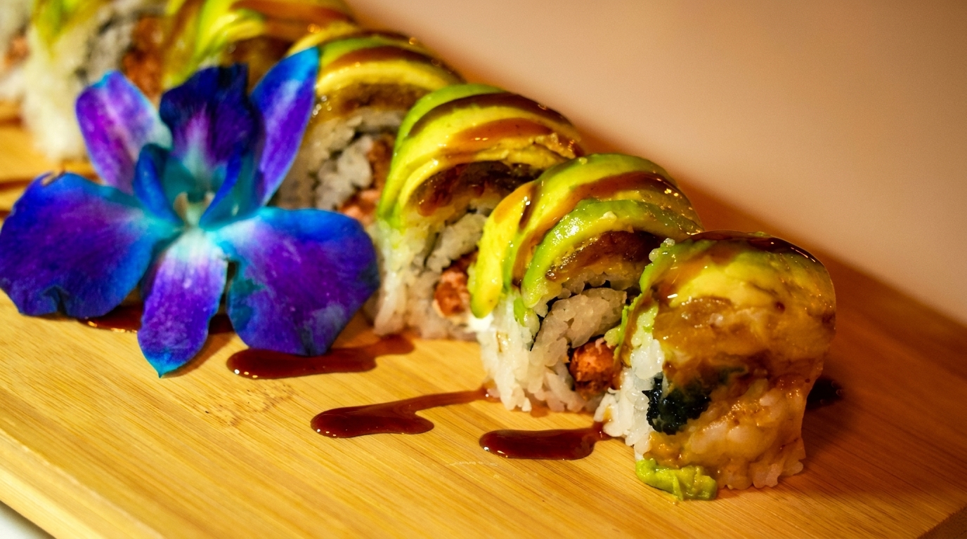 Dragon sushi rolls with avocado, eel sauce, and a purple orchid on a wooden board.