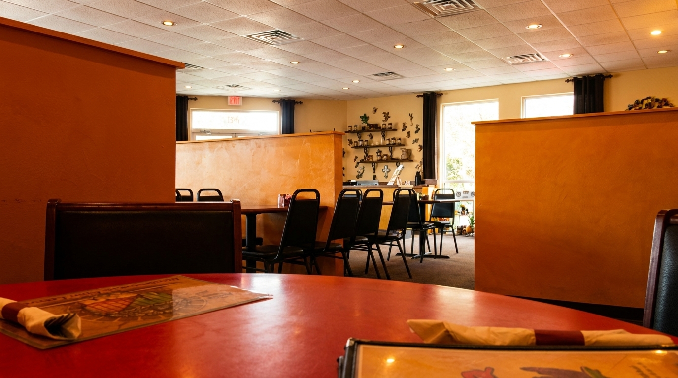Interior view of a restaurant with orange walls, red tables, black chairs, and decorative shelves.