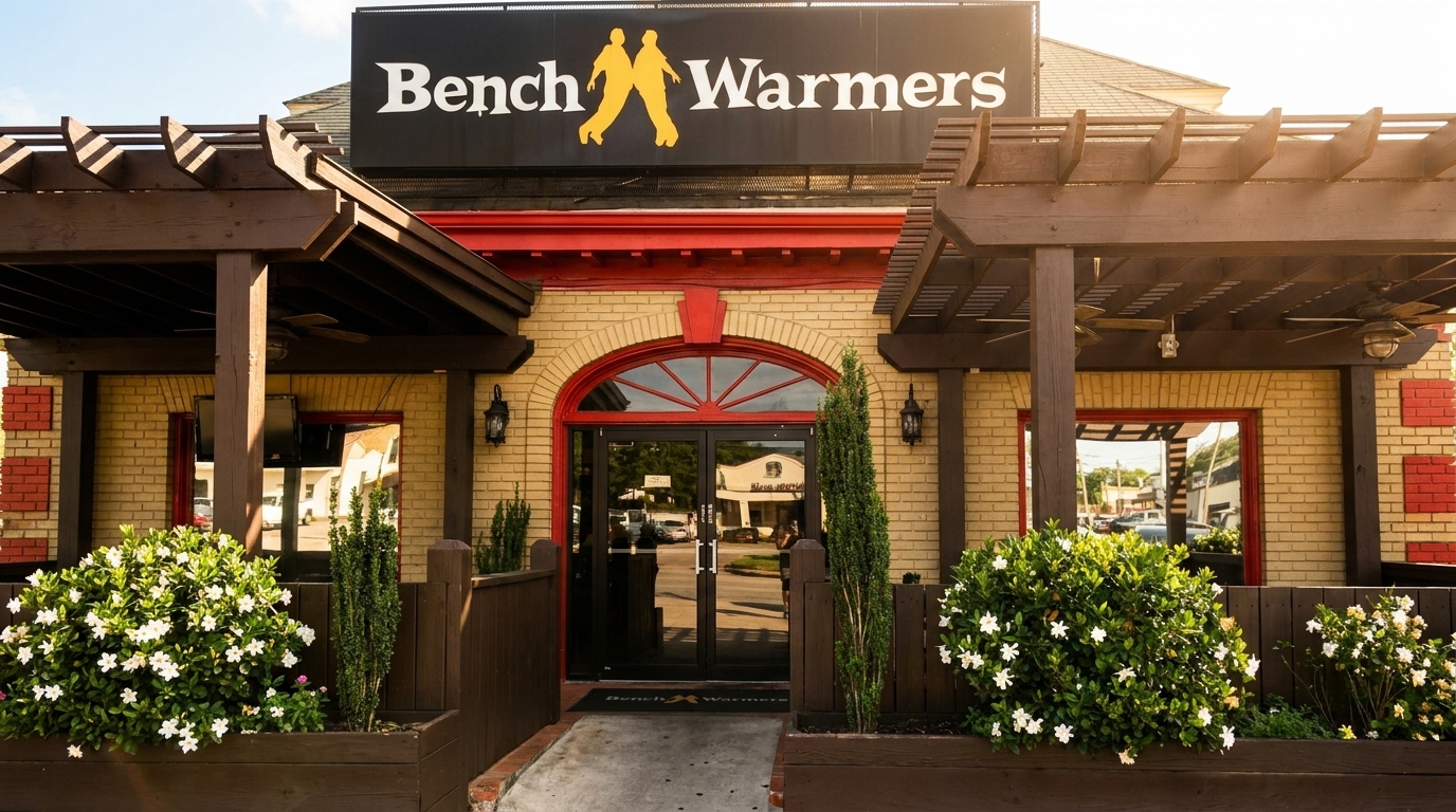 Exterior of Bench Warmers restaurant with a large sign, arched entrance, and outdoor patio.