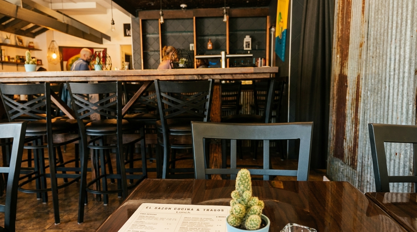 Restaurant interior with a wooden table, menu, cactus, and bar stools, with people in the background.