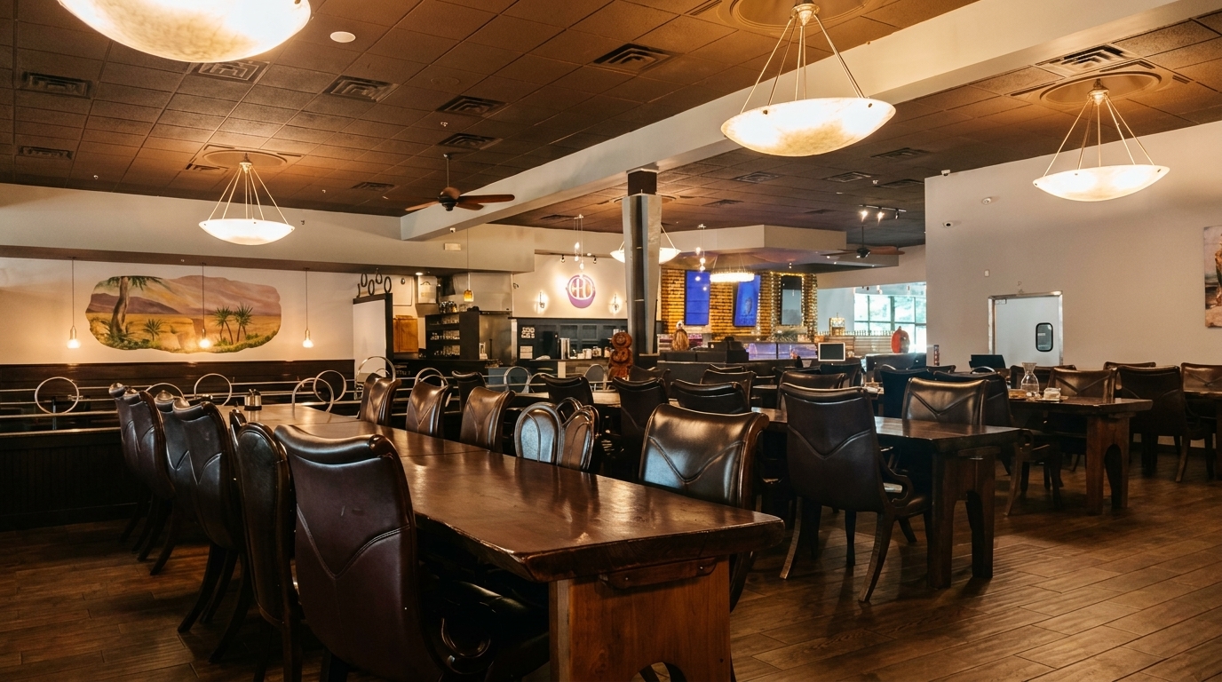 Spacious restaurant interior with dark wood tables, leather chairs, and a desert mural on the wall.