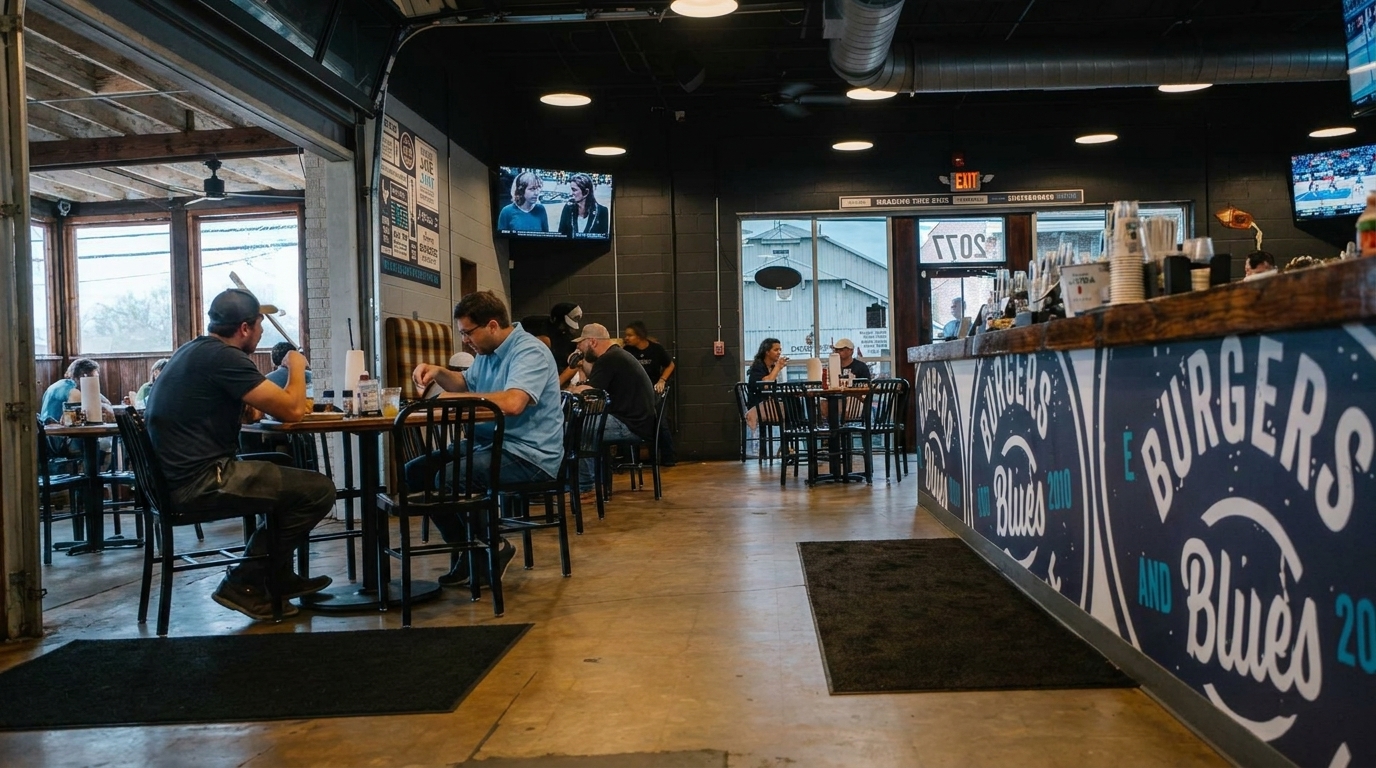 Diners seated at tables in a casual restaurant with a "Burgers and Blues" counter.