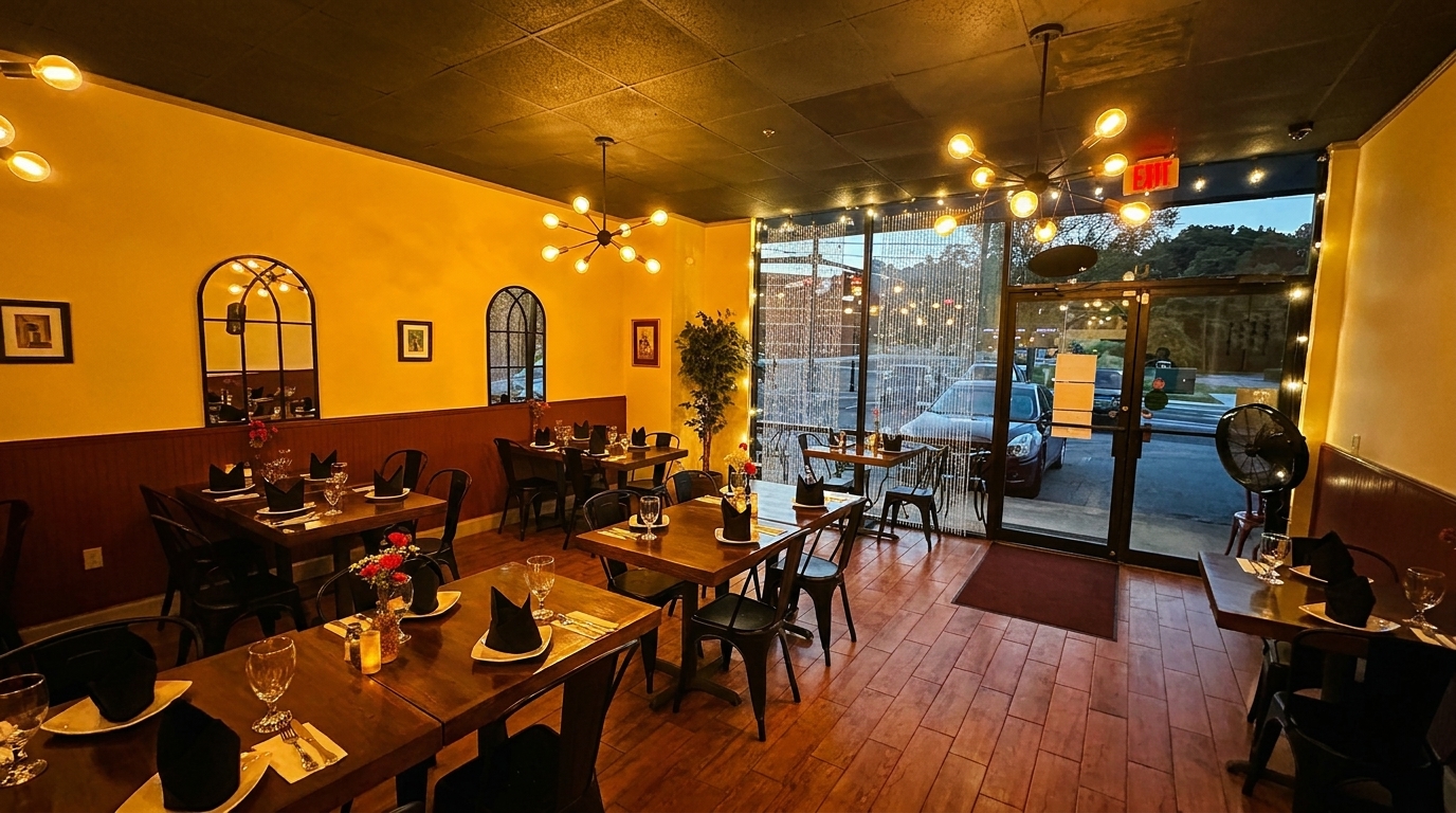 Cozy restaurant interior with warm yellow walls, dark wood tables set for dining, and large front windows.