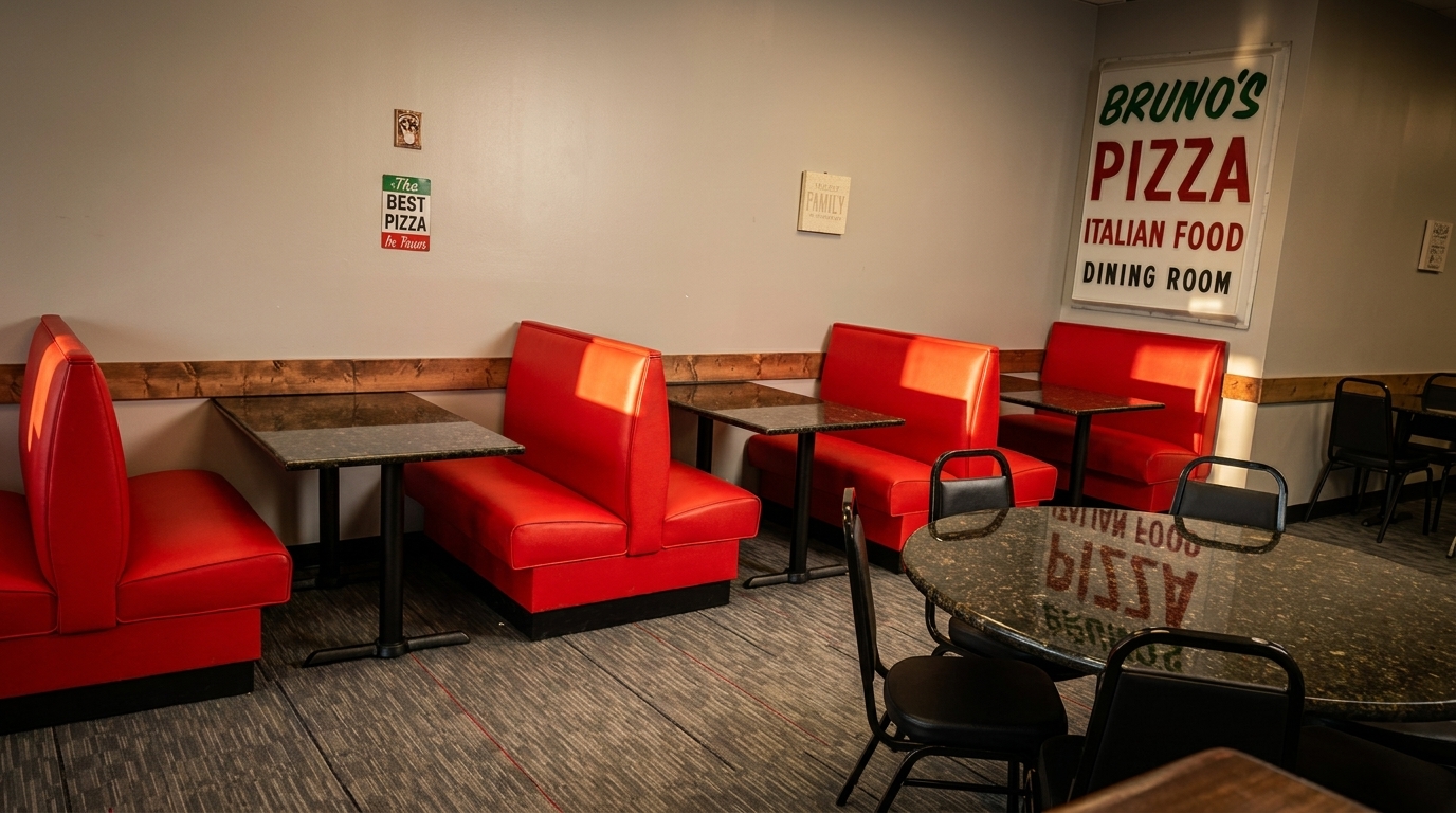 Interior of Bruno's Pizza dining room with red booths, black tables, and a large sign.