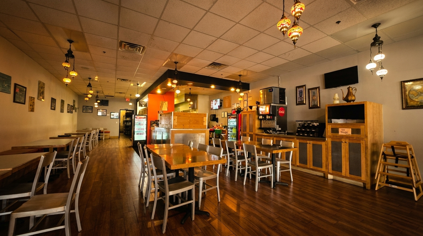 Interior of a restaurant with wooden tables, metal chairs, and decorative hanging lamps.