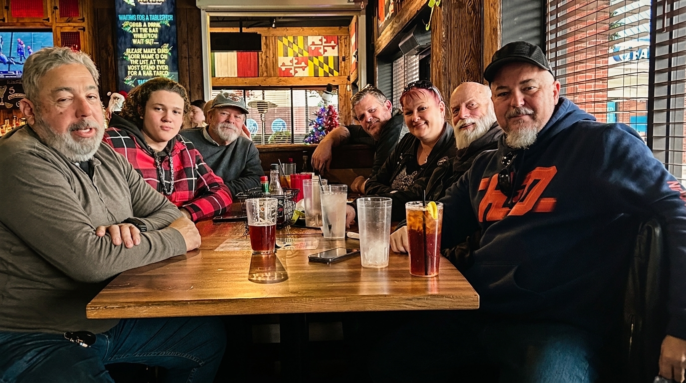 Seven people, including men and women, are seated around a wooden table in a restaurant, with drinks.