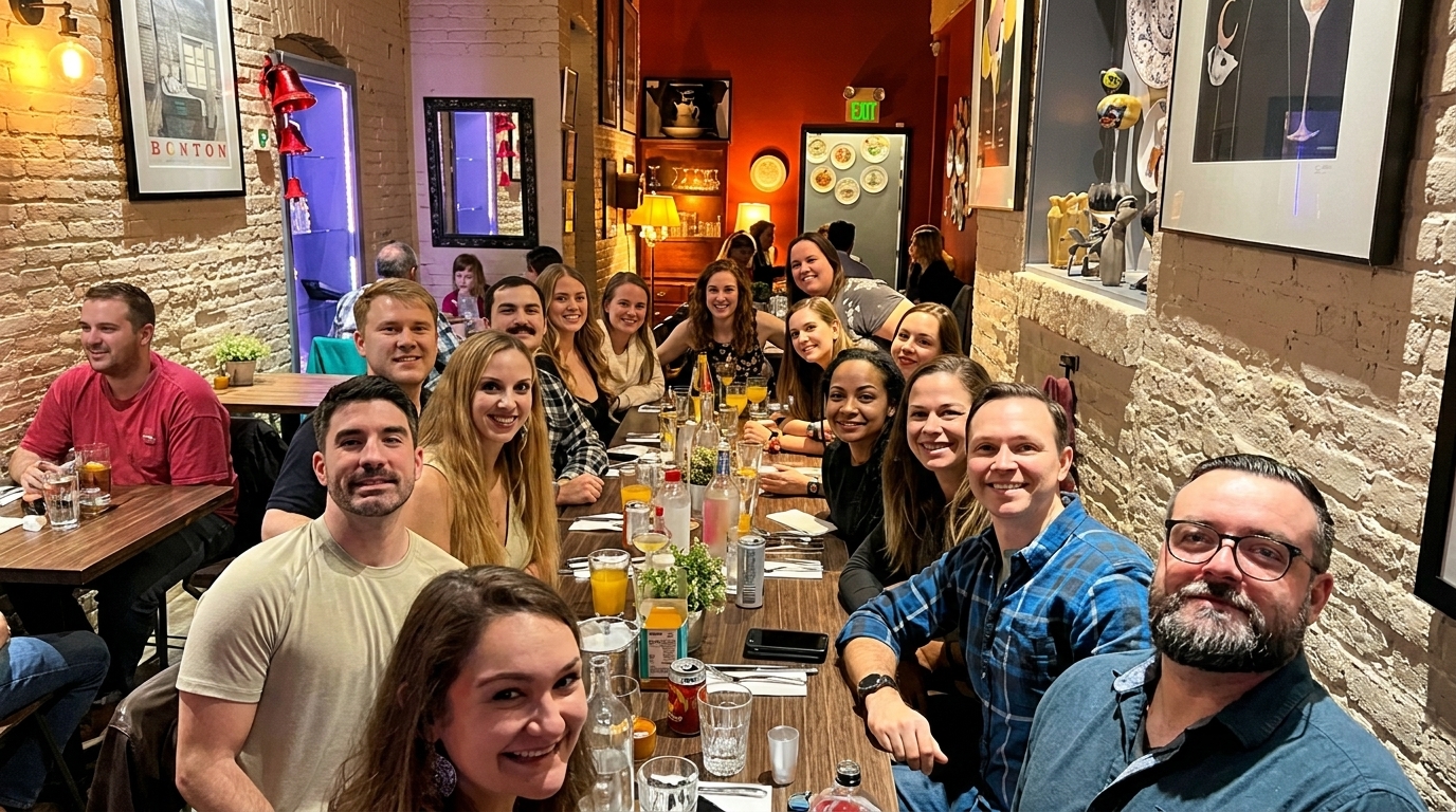 A large group of smiling people gathered around a long dining table in a restaurant.