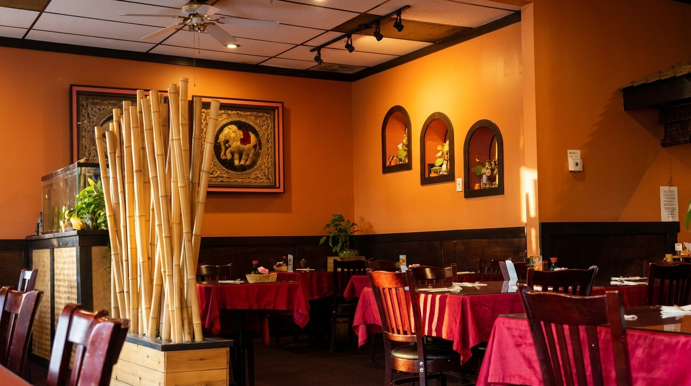 Restaurant interior with orange walls, red tablecloths, dark wood chairs, and bamboo decor.