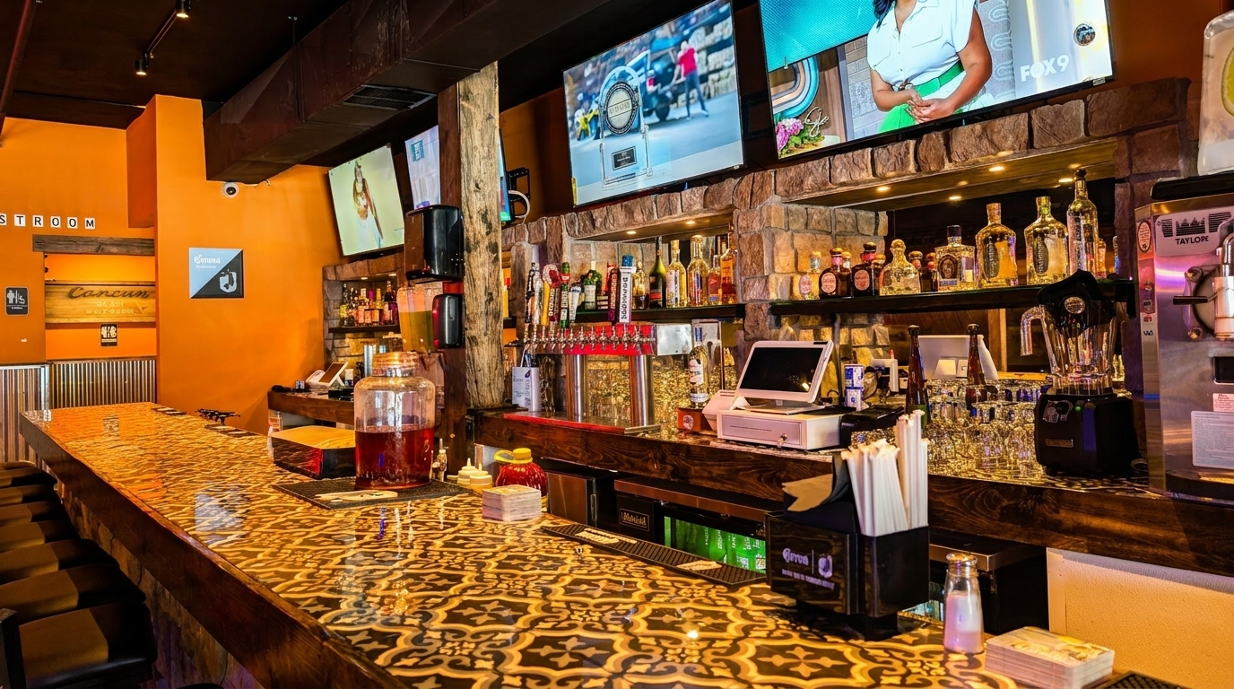 Vibrant bar interior with an ornate countertop, multiple TVs, and a well-stocked liquor and beer tap display.