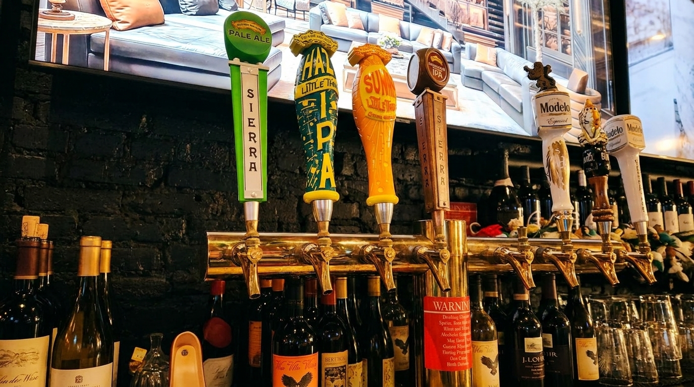 A row of beer taps with various brand handles, including Sierra and Modelo, above wine bottles.