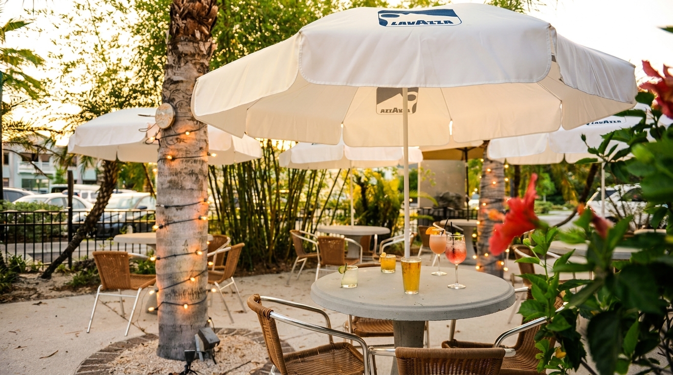 Outdoor patio with white umbrellas, string lights on palm trees, and cocktails on tables.