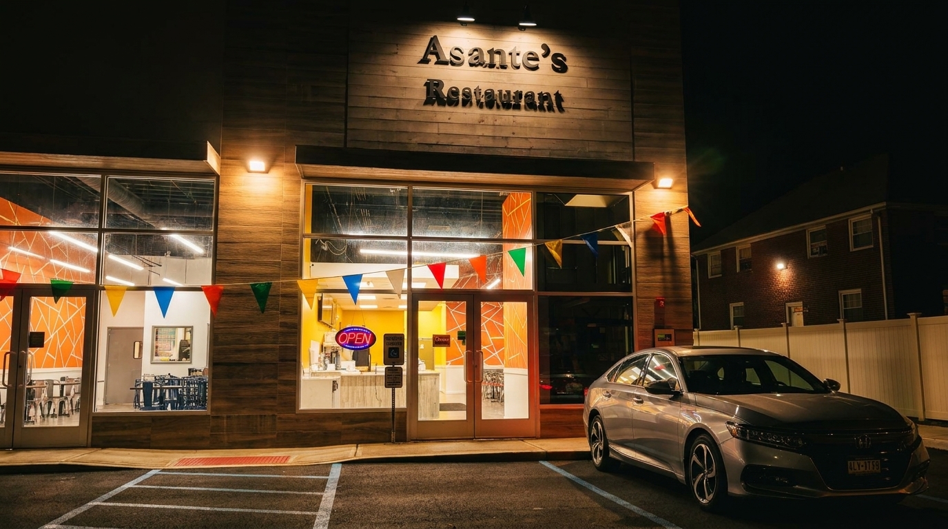 Asante's Restaurant exterior at night, with a silver car parked in front and colorful bunting.