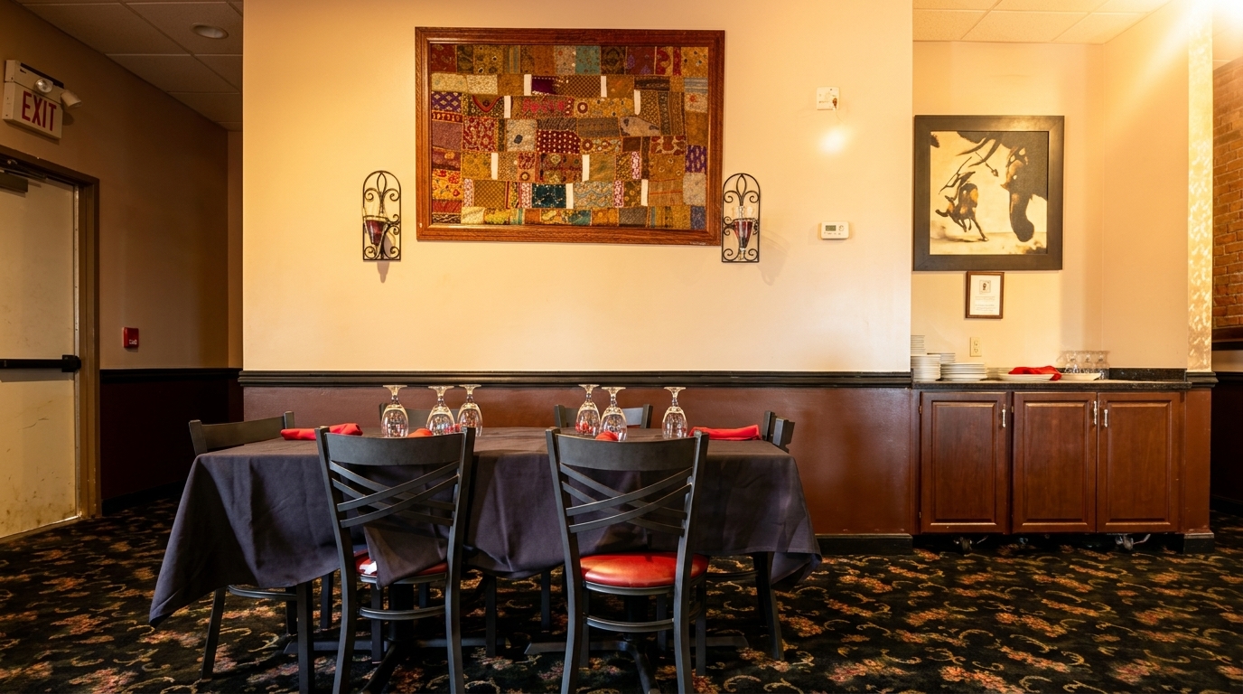 A restaurant dining area with a set table, patterned carpet, and decorative wall art.