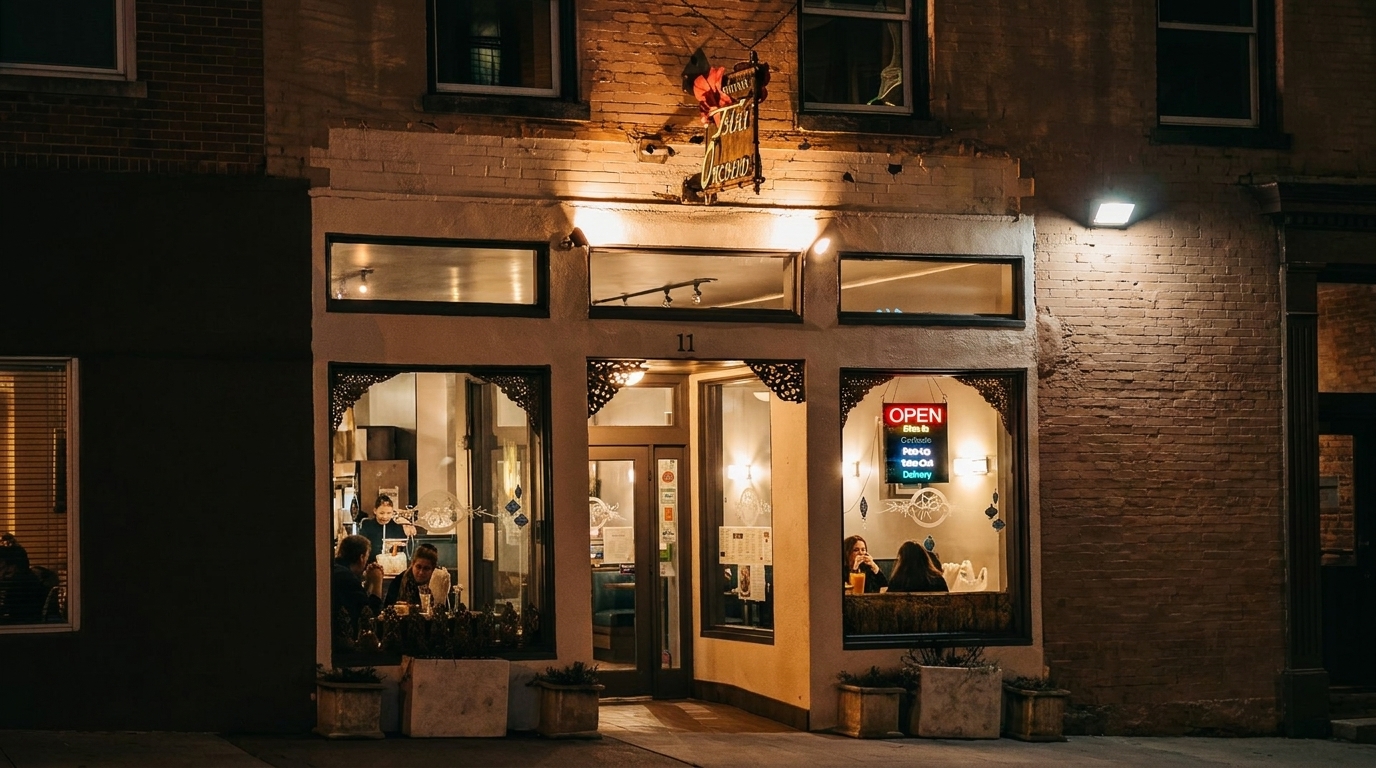 Exterior of a restaurant at night, with warm light spilling from windows onto the street.