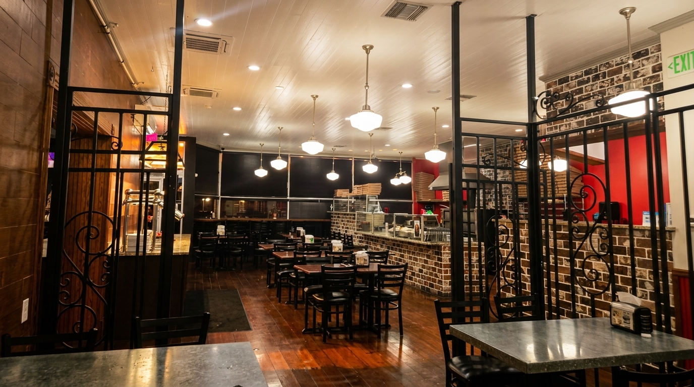 Interior view of a restaurant with dark wood floors, brick walls, and pendant lights.