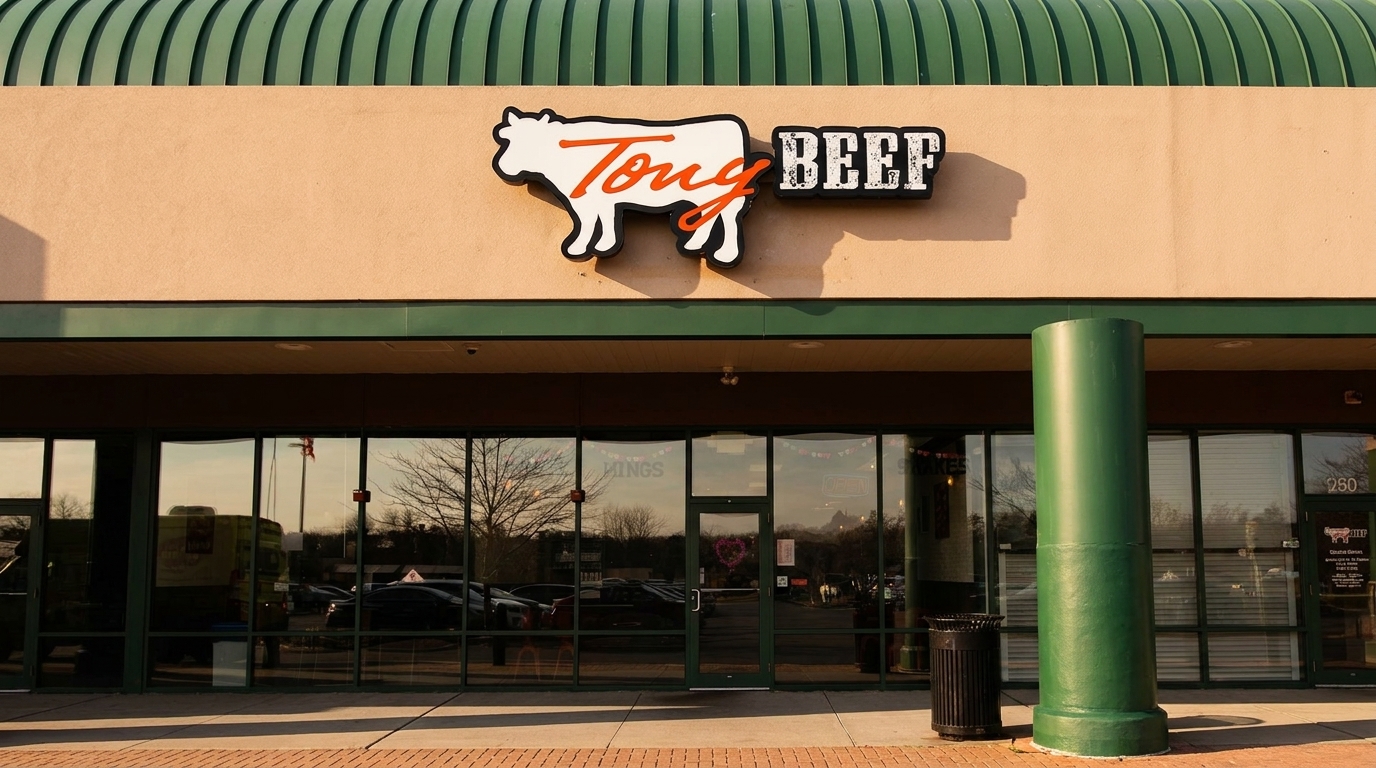 Exterior of Tony Beef restaurant with a cow-shaped sign, large windows, and a green awning.