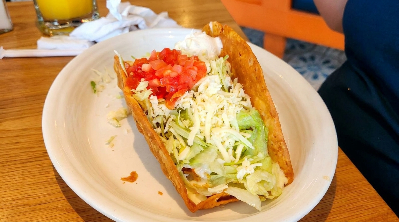 Crispy taco filled with ground beef, lettuce, shredded cheese, diced tomatoes, and sour cream.