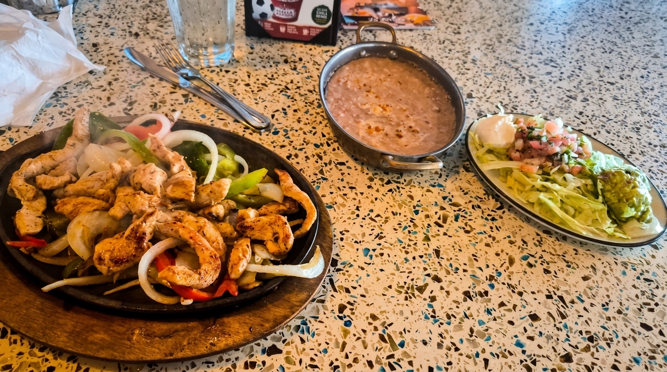 Sizzling chicken and shrimp fajitas with onions and peppers, served with refried beans and toppings.