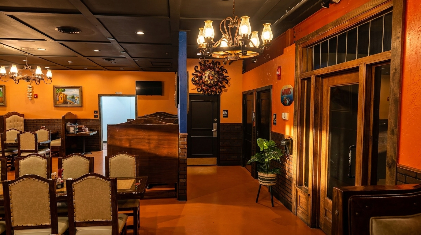 Warmly lit Mexican restaurant interior with orange walls, dark wood furniture, and decorative chandeliers.