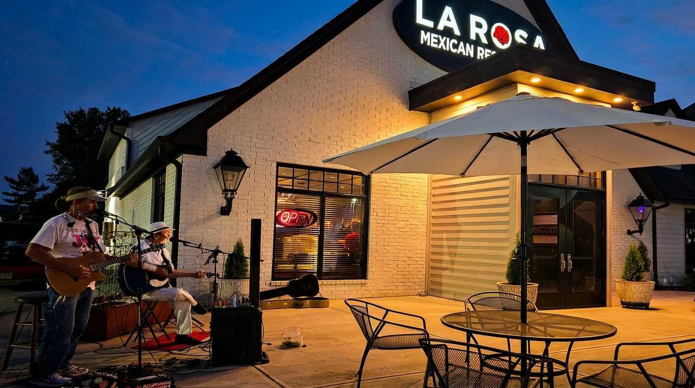 Two musicians playing guitars on a patio outside La Rosa Mexican Restaurant at dusk.