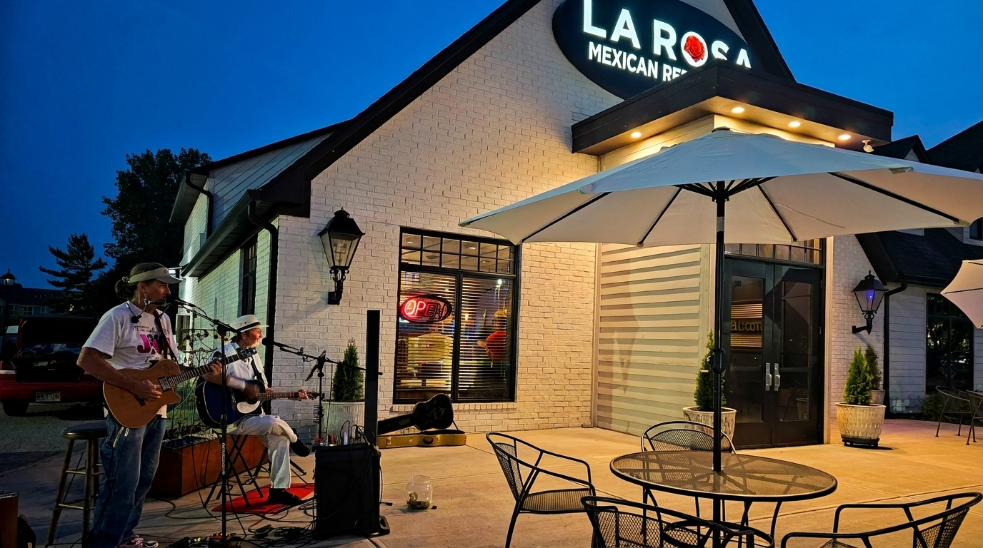 Two musicians play guitars on a patio outside La Rosa Mexican Restaurant at dusk.