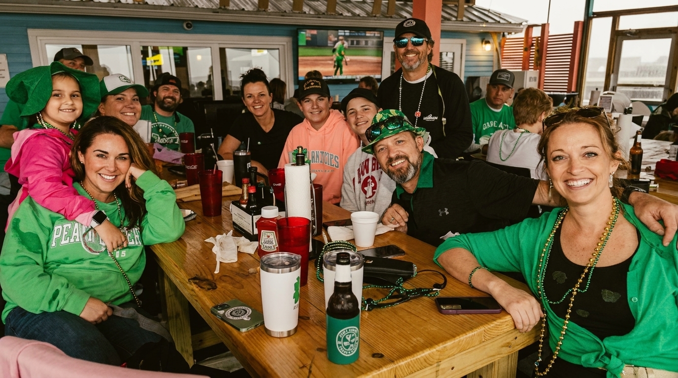 A large group of people in green attire and beads smiling at a wooden table.